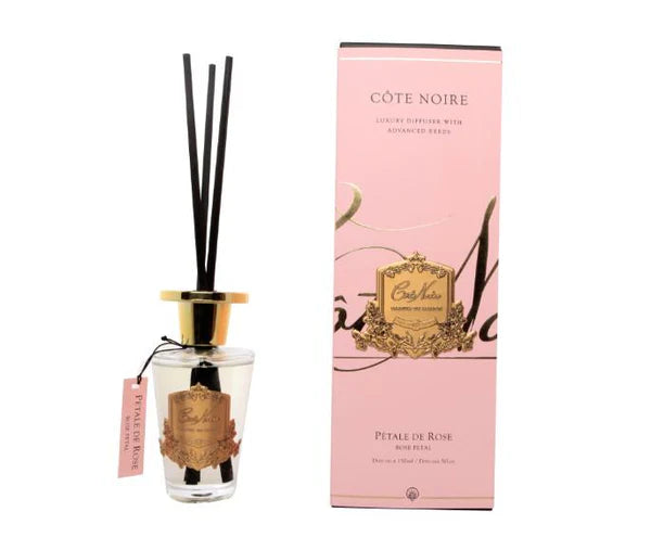 schwarze duftstaebchen im glas mit goldenem deckel und emblem. pinke verpackung. rose petal.